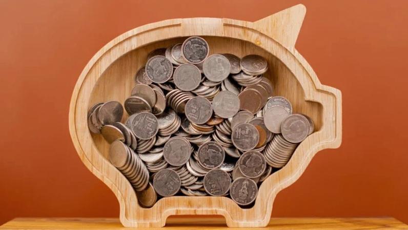 Moedas aparecem dentro de um cofrinho de madeira.
