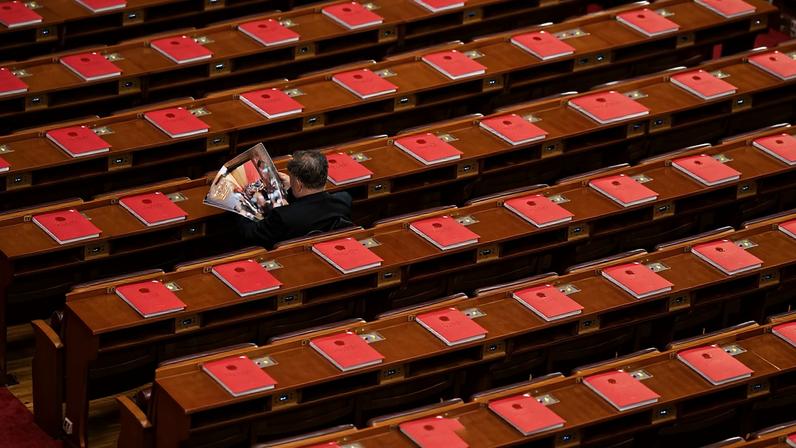 Red books are seen on the desks as a delegate reads a magazine before the closing session of the National People’s Congress in Beijing.