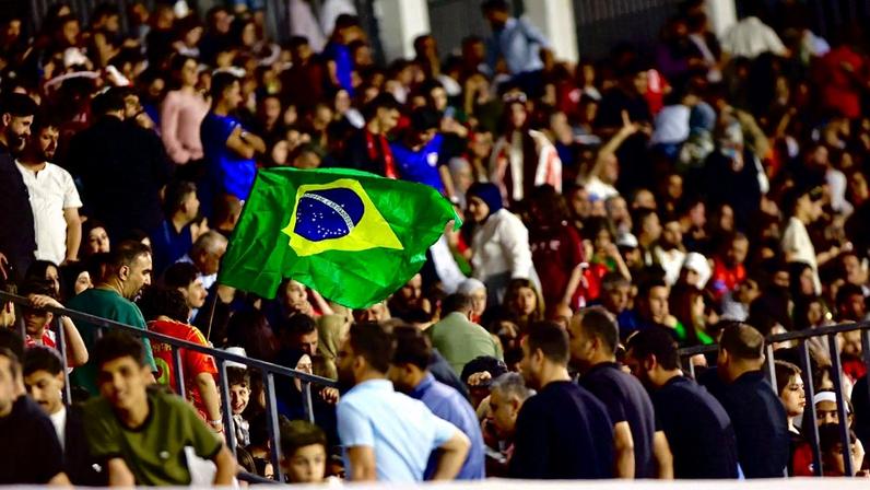 Torcedores com bandeira do Brasil durante partida do Newroz no Iraque