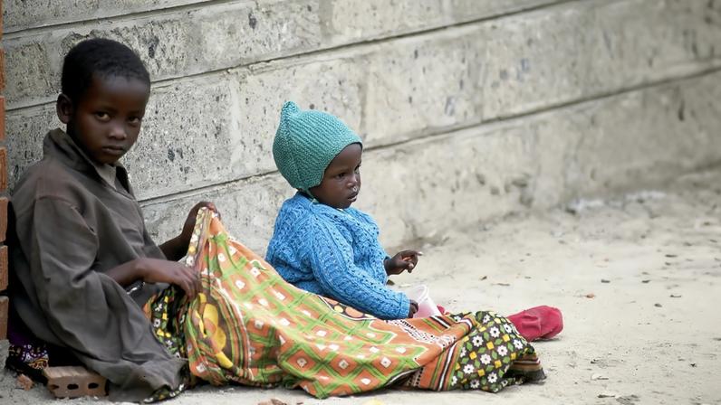 Two Kenyan children sitting on the streets of Nairobi.