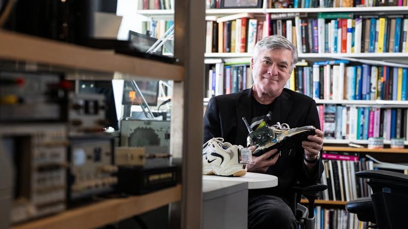 Professor Joseph Paradiso sits in his office holding an electronics-infused sneaker, a wearable technology prototype developed for sensing and interactive applications.