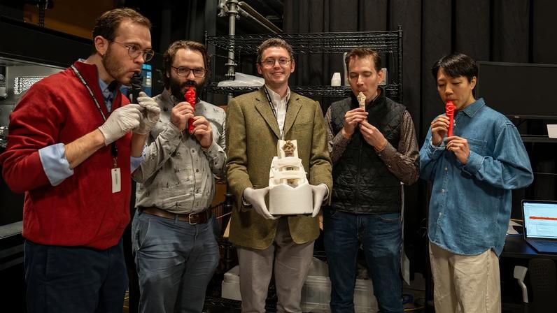 Nate Steele, Mark Rau, Jared Katz, Benjamin Sabatini, and Jin Woo Lee stand in a semicircle. Four are blowing into replica whistles, while one holds an ancient whistle in a protective cradle.