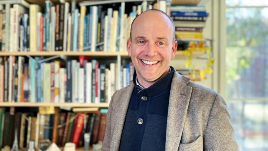 John Ochsendorf standing in front of a bookcase