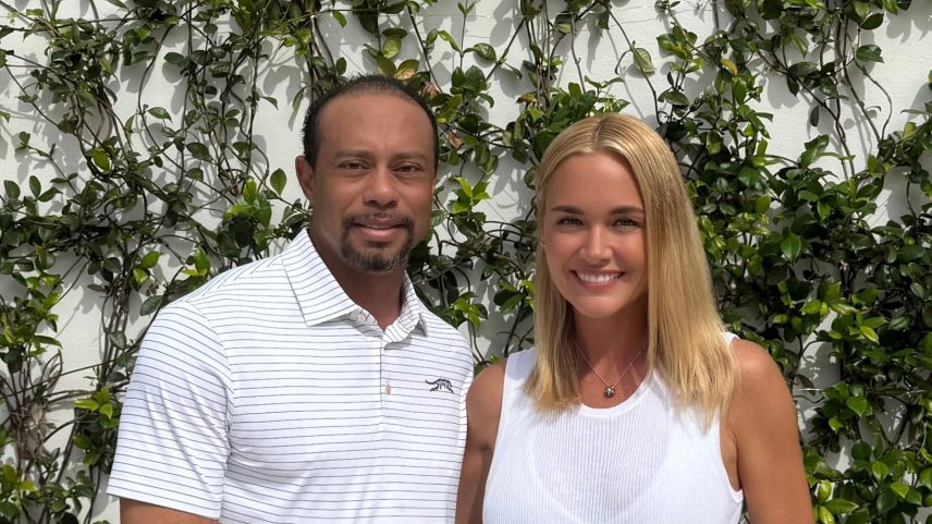 Tiger Woods and Vanessa Trump smiling, standing against a white wall with vines.