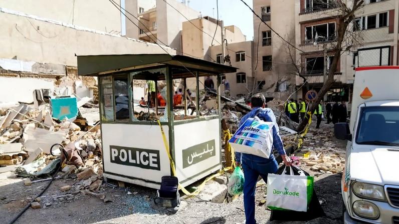 An Iranian man walks past debris from a destroyed building following a missile strike on Tehran.