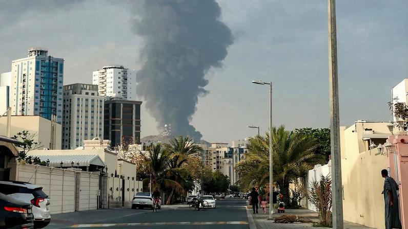A cloud of smoke rises above city buildings.