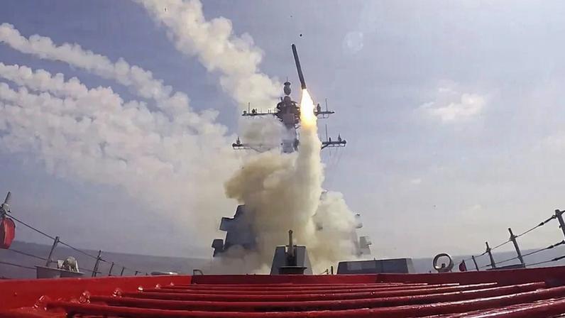 A missile fires from a military ship at sea.