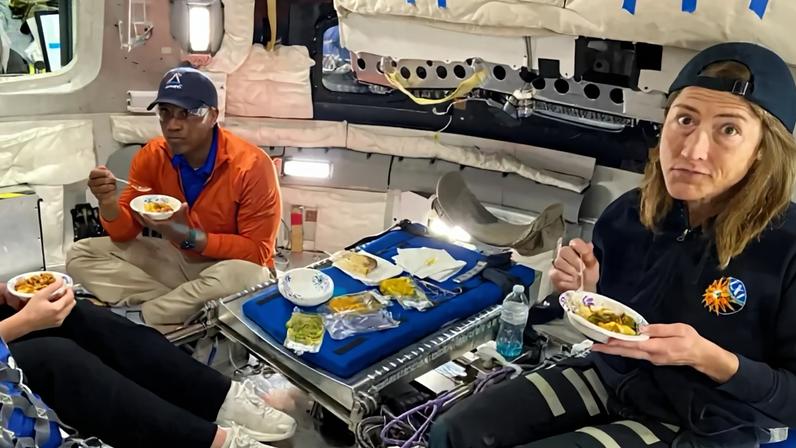 Victor Glover e Christina Koch, da Nasa, comendo durante uma simulação do voo espacial.