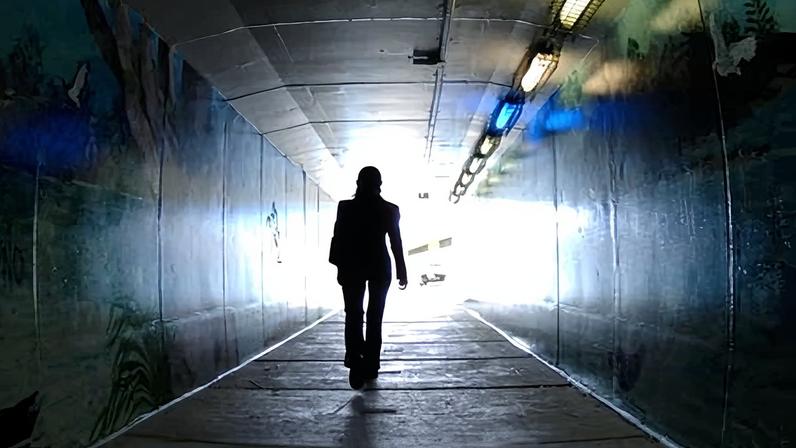 Woman walking through a dark tunnel alone