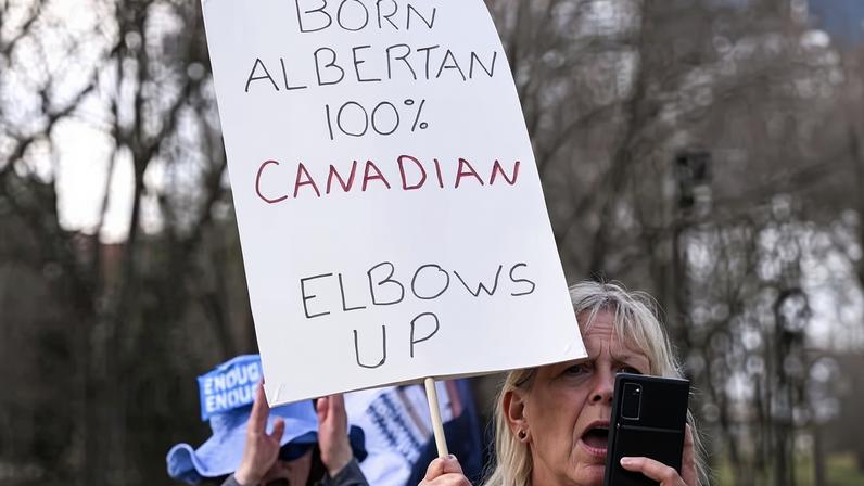 A participant holds a placard as hundreds gather for a Resistance Rally organized by the Alberta Federation of Labour (AFL) to protest issues including wages human rights concerns and separatist rhetoric, at the Alberta legislature in Alberta, Canada, on 26 April 2025.