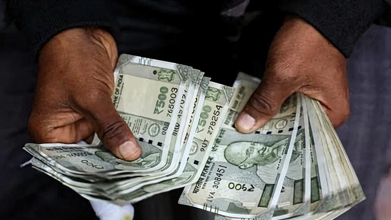 Man counting Indian currency notes at a roadside exchange stall in Delhi. The IMF says market-based finance is ‘increasingly sensitive to global risk conditions’.