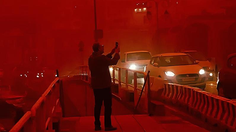 A man takes pictures as the city of Heraklion that is covered in red dust coming from Africa