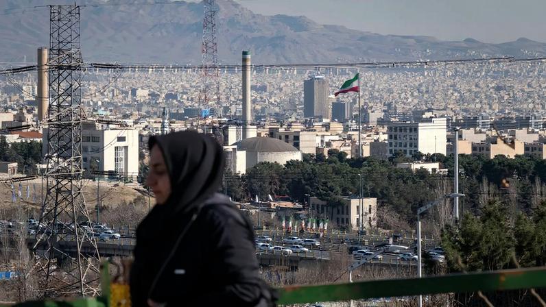 An Iranian woman walks past a view of Tehran's research reactor in Tehran.