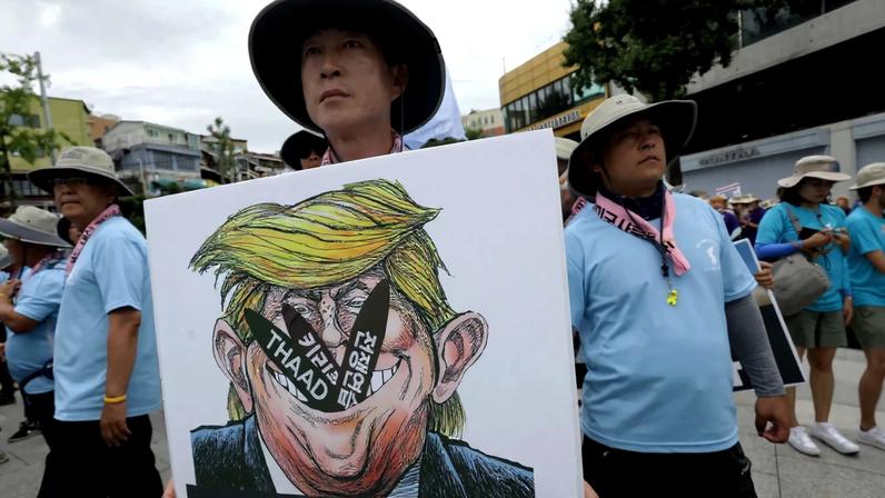 A South Korean protester holds a placard with an illustration of U.S. President Donald Trump during a rally against the deployment of the Terminal High-Altitude Area Defense (THAAD) system near the U.S. Army base in in Seoul on Aug. 14, 2017.