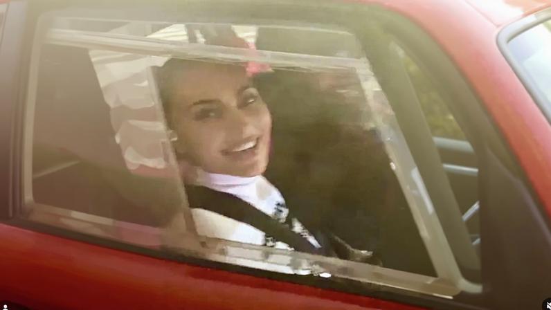 Kim Kardashian smiling while riding in a car.