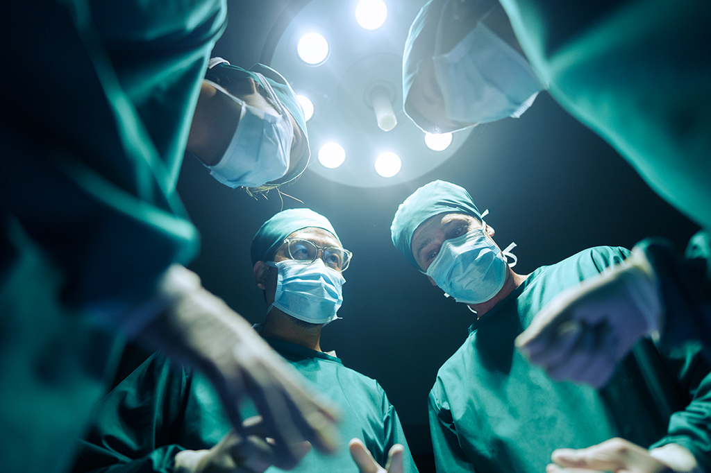 Foto de stock de ângulo baixo Quatro cirurgiões coordenando seus casos cirúrgicos Na sala de cirurgia, trabalho em equipe e cooperação
