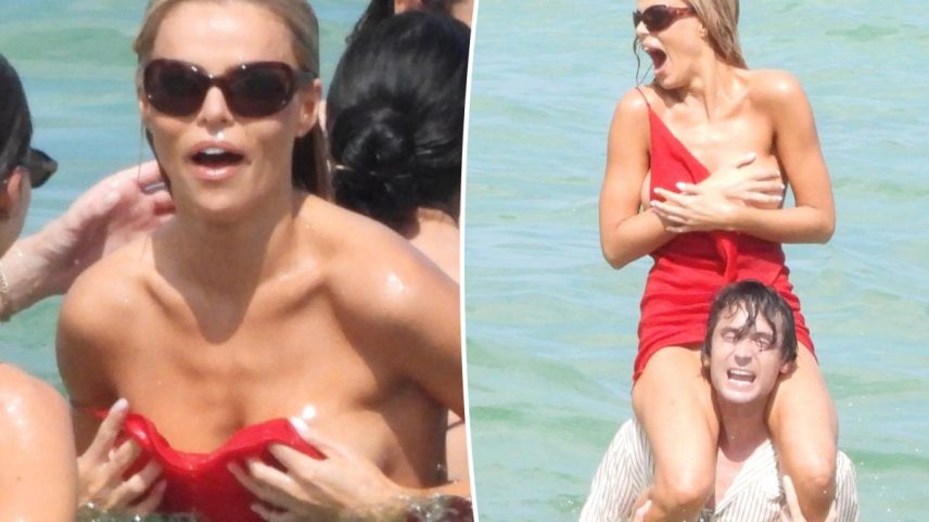 Brooks Nader in a red dress covering herself on a man's shoulders, yelling in the water.