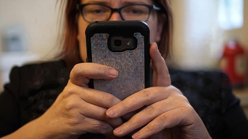 A woman holds a smartphone up in front of their face