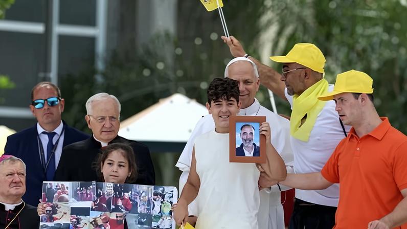 Pope Leo XIV, behind boy holding framed photograph, during a visit to Acerra in Italy.