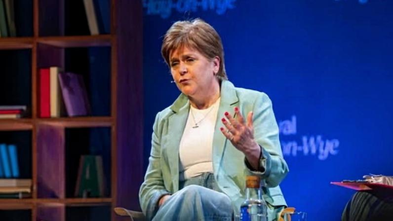 Nicola Sturgeon sitting on a stage.