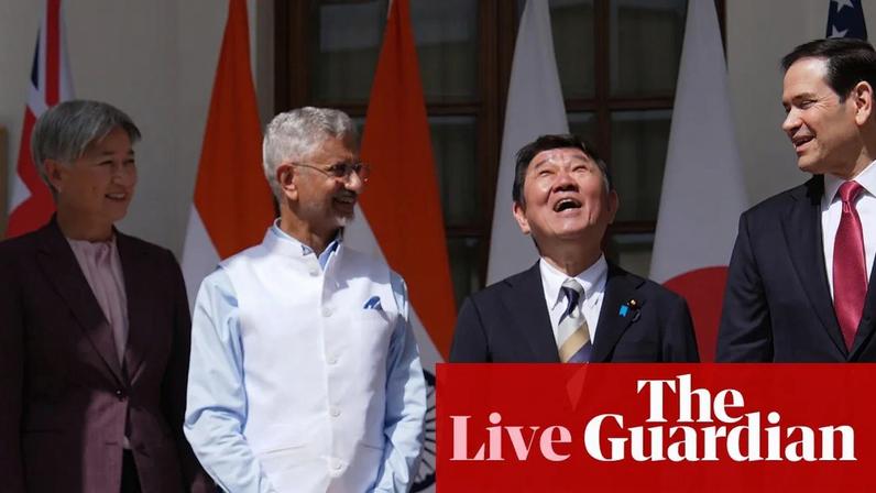Penny Wong, S Jaishankar, Toshimitsu Motegi and Marco Rubio dressed in formal attire stand together laughing, with flags visible behind them