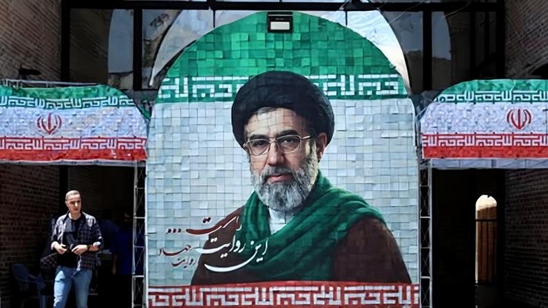 An Iranian walks past a picture of Iranian supreme leader Ayatollah Mojtaba Khamenei in a street in Tehran on 18 May 2026.