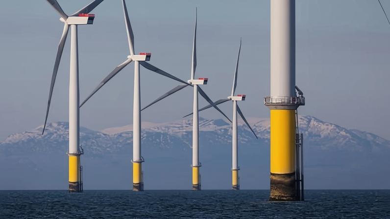 Wind turbines of an offshore wind farm with the Lake District in the background
