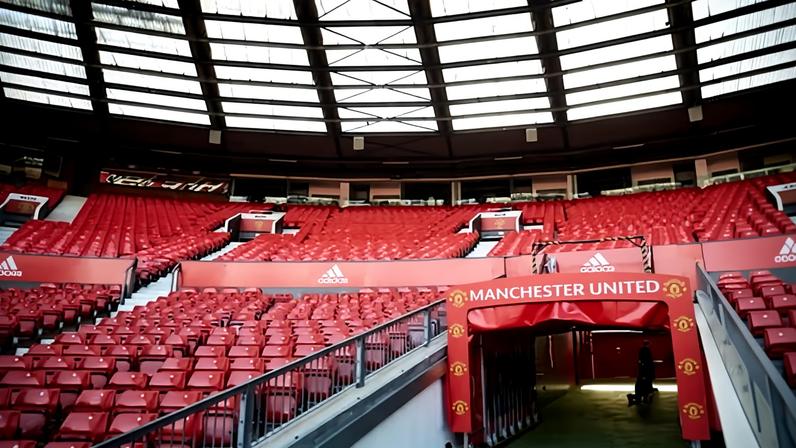 The Manchester United stadium tunnel entrance, with red seats rising in tiers and a curved glass roof above