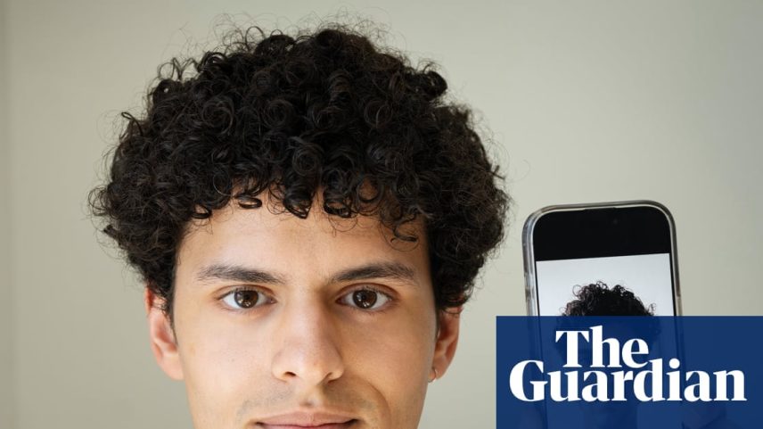 Isaaq Tomkins holding up a mobile phone showing a radically altered image of his face