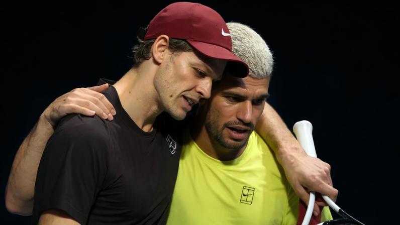 Italiano Jannik Sinner é abraçado pelo espanhol Carlos Alcaraz após a vitória na decisão do ATP Finals de Turim (Photo by Marco BERTORELLO / AFP)