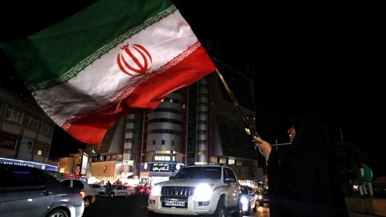 Uma mulher acena com uma bandeira iraniana durante um comício em apoio ao líder supremo do Irã, Aiatolá Mojtaba Khamenei, na Praça Sadeghyeh, em Teerã, em 27 de abril de 2026. O principal diplomata do Irã culpou Washington em 27 de abril pelo fracasso das negociações de paz no Oriente Médio durante uma visita à Rússia, onde o presidente Vladimir Putin lhe prometeu o apoio de Moscou para acabar com a guerra.