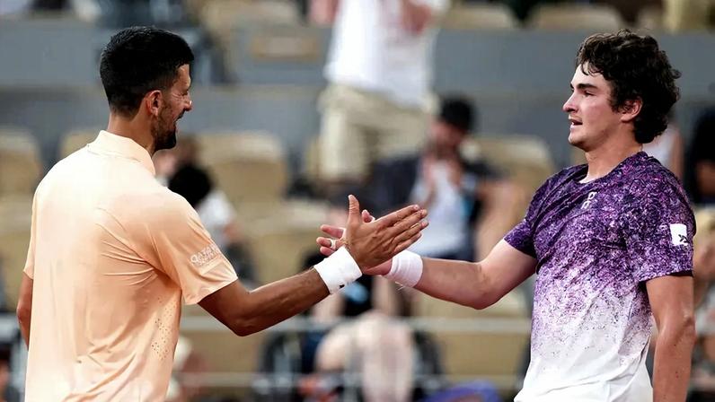 O vencedor, o brasileiro João Fonseca (à direita), cumprimenta o sérvio Novak Djokovic ao final da partida de simples masculina no sexto dia do torneio de tênis de Roland Garros, na quadra Philippe-Chatrier, em Paris (Foto: Dimitar Dilkoff / Afp)