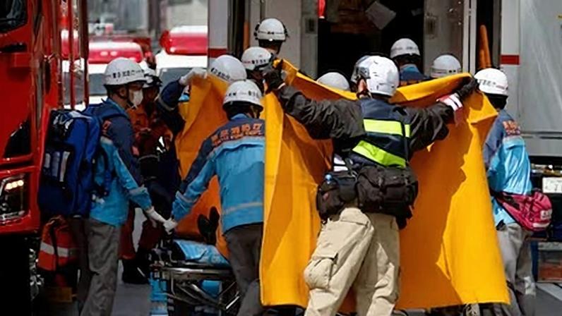 El personal de emergencias extiende mantas para proteger a una persona que es trasladada fuera del complejo comercial de lujo Ginza Six, en el barrio de Ginza, Tokio (Japón), este lunes.