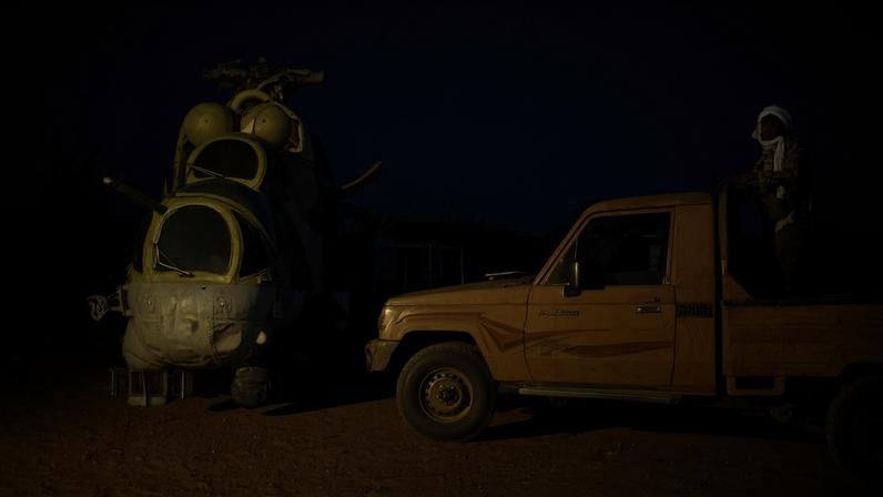An Azawad Liberation Front militant stands on a pickup truck next to a damaged Russian Mi-24 helicopter at the former Africa Corps barracks in Kidal, Mali, on May 6.
