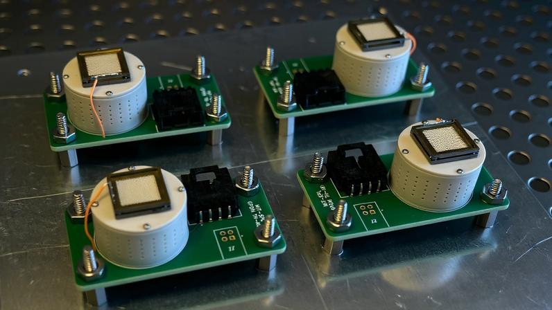Four flight unit electrospray thrusters, each comprised of a simple circuit board with a small cyllindrical tank, are bolted to a metal sheet