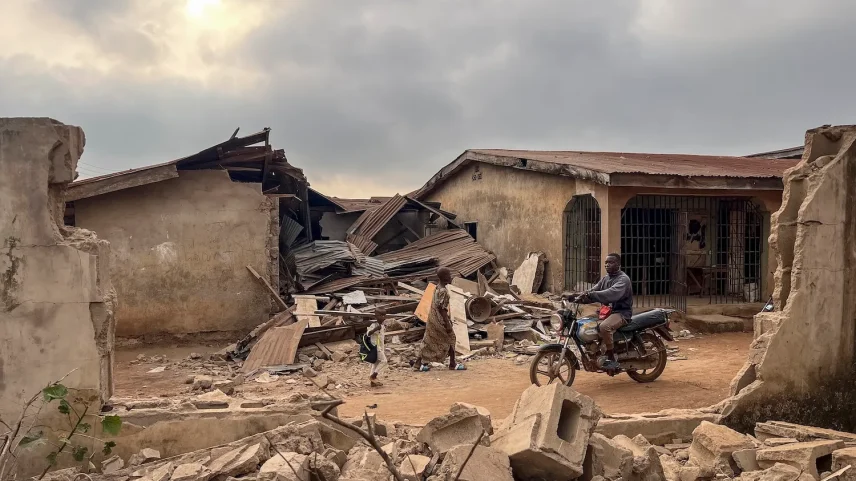 People move past destroyed buildings in Offa, Nigeria, on Dec. 27. The damage was caused by debris from expended munitions that fell from U.S. strikes on militants linked to the Islamic State in Nigeria.