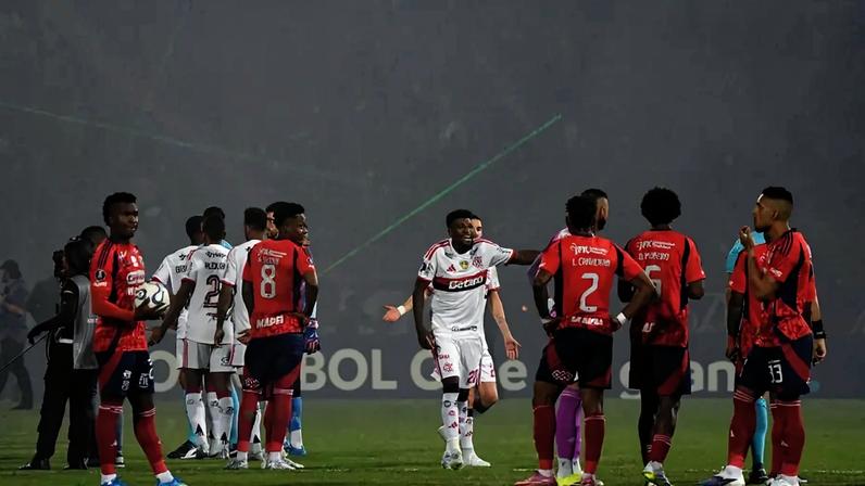Jogadores de Flamengo e Independiente Medellín em campo durante a confusão no Estádio Atanasio Girardot (Foto: Jaime SALDARRIAGA / AFP)