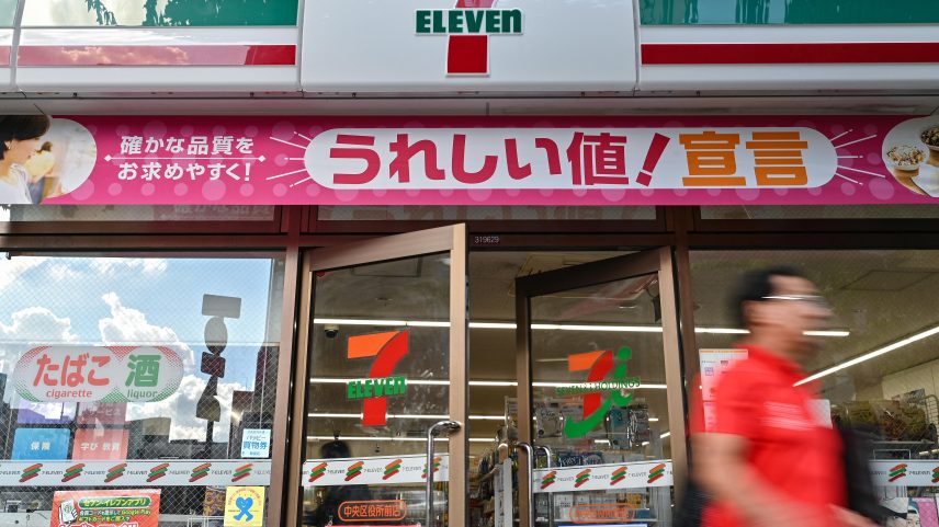 A man walks out of a 7-Eleven convenience store along a street in central Tokyo.