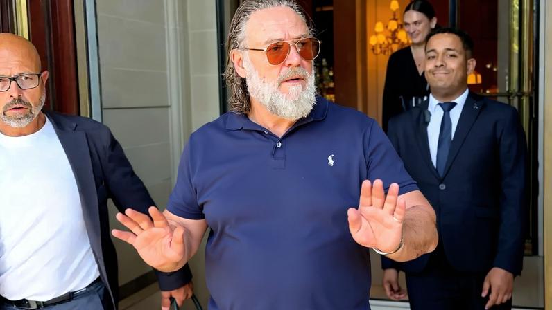 Russell Crowe holding up his hands, preventing fans from approaching him for autographs.