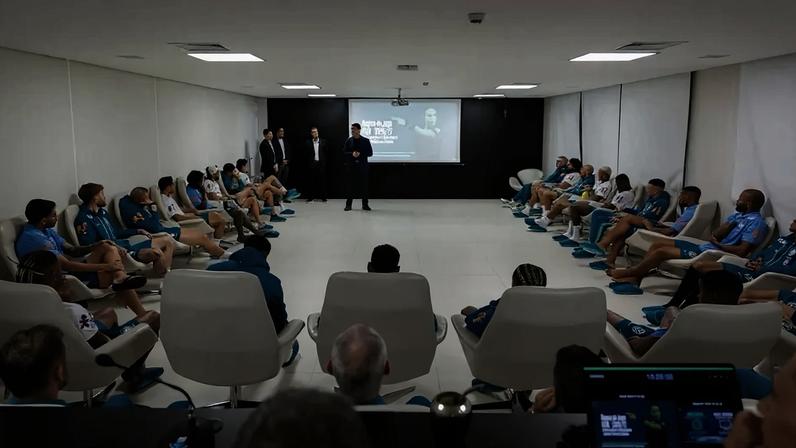 Jogadores brasileiros sentados em cadeiras assistindo palestra