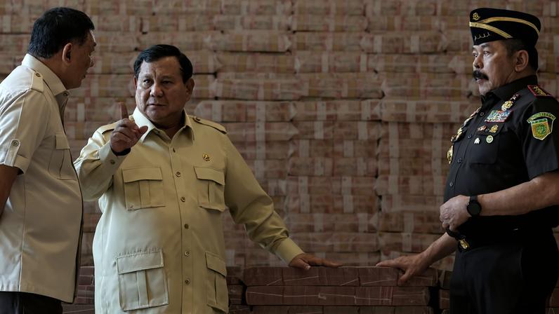 Indonesian President Prabowo Subianto, center, speaks while flanked by Attorney General Sanitiar Burhanuddin, right, and Minister of Defense Sjafrie Sjamsoeddin, left, beside stacks of Indonesian rupiah banknotes equivalent to $800 million during the handover of assets recovered from a corruption case involving the provision of crude palm oil export facilities, in Jakarta on Oct. 20, 2025.