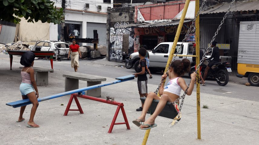 Crianças brincam na Vila Cruzeiro, no Rio, ao lado de barricadas colocadas para conter avanço de policiais durante operação. — Foto: Tânia Rêgo/Agência Brasil