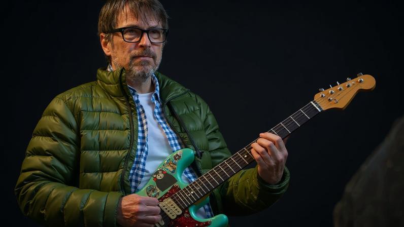 Rivers Cuomo, holding an electric guitar.