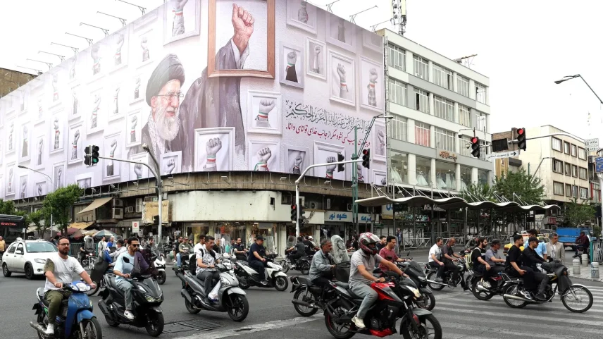 Iranians drive past a billboard carrying the image of the late Iranian Supreme Leader Ali Khamenei, killed in February 2026 in a military attack by the US and Israel on Iran, in a street in Tehran on May 5.