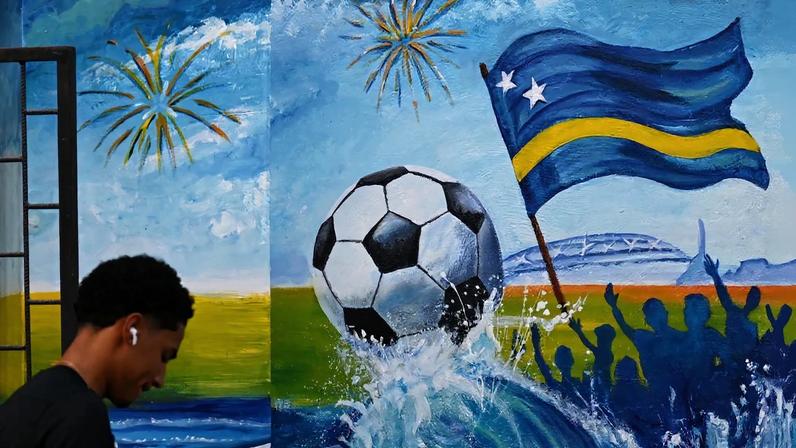 A man walks past a mural depicting a football and a flag of Curaçao in Willemstad, Curaçao, on April 10.
