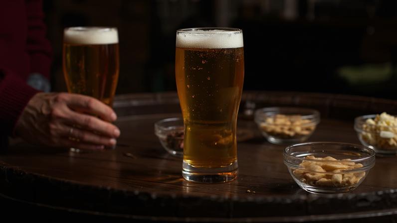 Copos de cerveja e amendoim sob uma mesa de madeira em um pub.