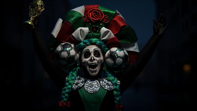 A woman dressed as a Catrina holds up a replica of a World Cup trophy before the start of a Guinness World Record attempt for the world's largest Mexican Wave in Mexico City on June 6.