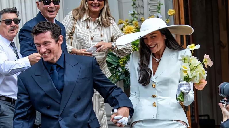 Dua Lipa and Callum Turner leaving their wedding ceremony as confetti falls.