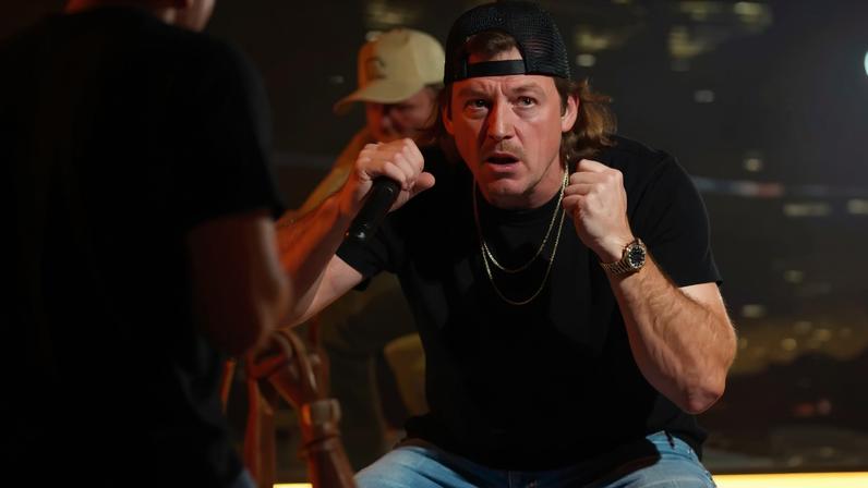 Morgan Wallen on stage throwing a fan's phone.