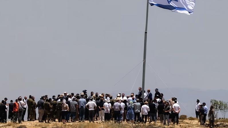 Israeli settlers raise the Israeli flag during an inauguration ceremony for a new settlement on Mount Tarousa in the occupied West Bank on Tuesday.